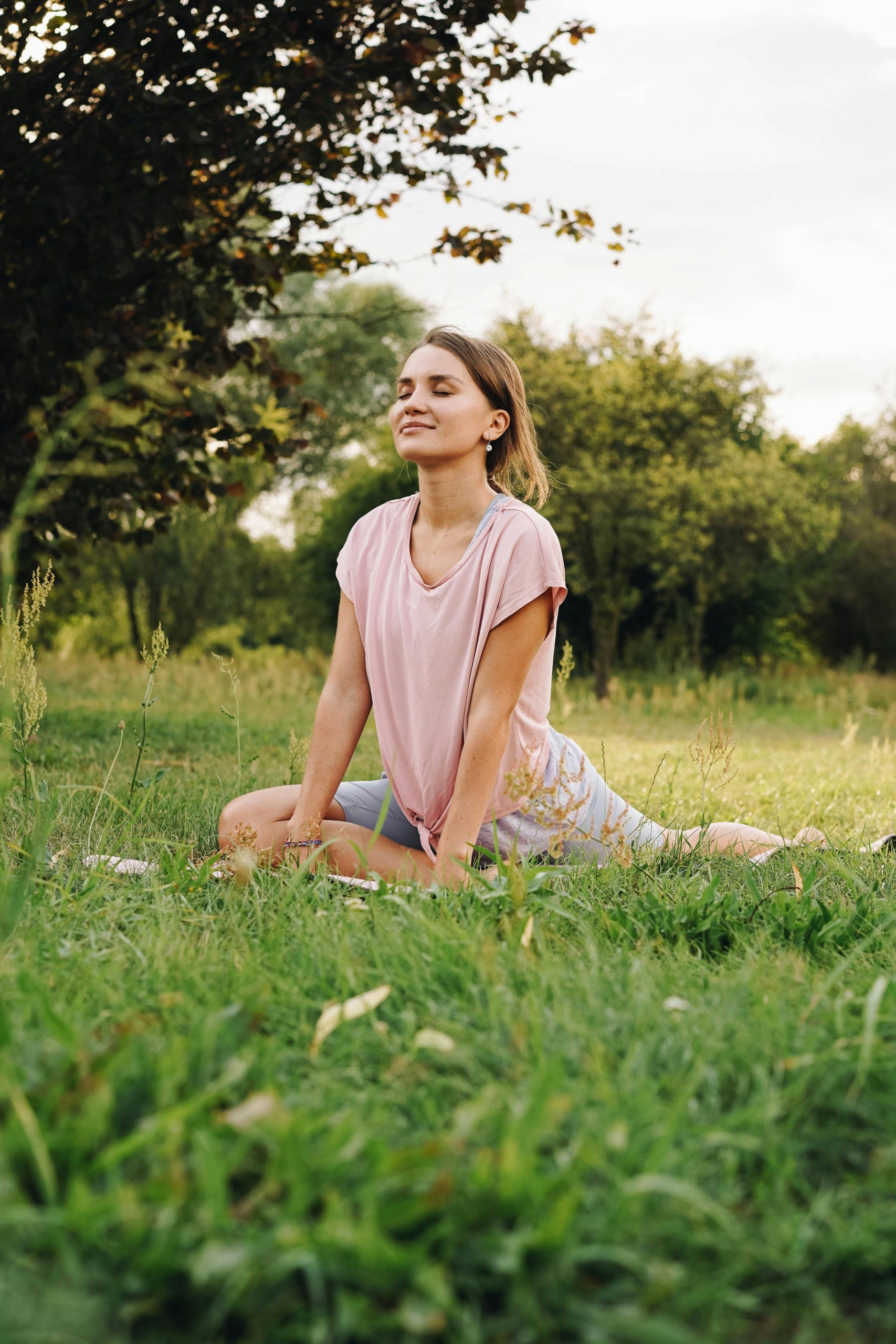 Adult woman meditating in a peaceful outdoor park setting, embracing healthy living and mindfulness.